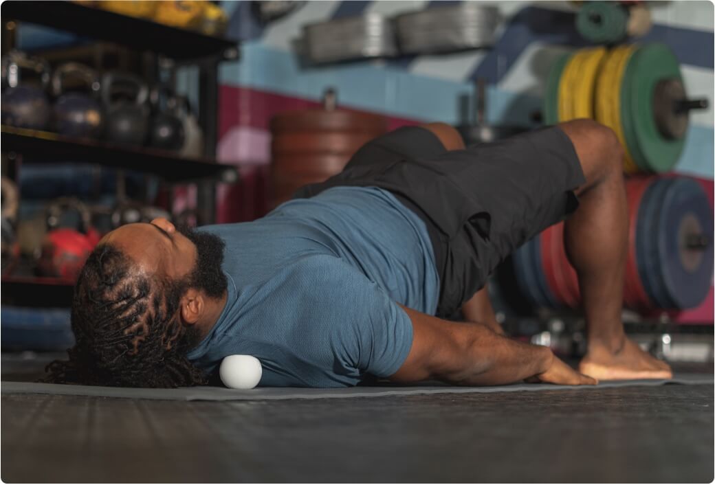 Man stretching neck and upper back using lacrosse ball trapezius muscle and fascia release technique