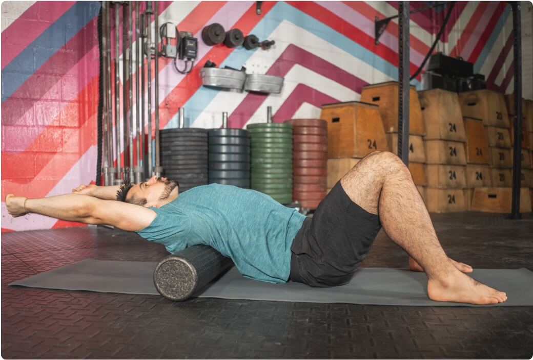 Man performing low back stretch with foam roller to decrease back pain